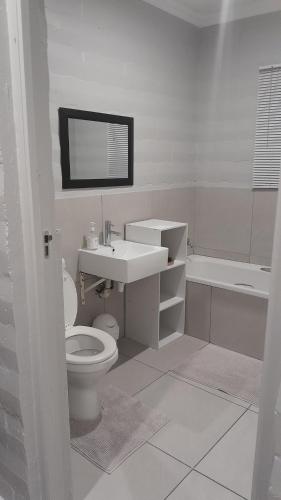 Biesiesvlei 1 في بليتنبيرغ باي: حمام أبيض مع حوض ومرحاض