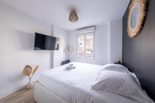 Schlafzimmer mit einem weißen Bett und einem TV in der Unterkunft Appartement Proche Disney Paris Vidéo-Projecteur in Bussy-Saint-Georges