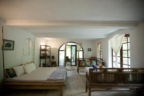 a bedroom with a bed and a couch and windows at Ancient House Cat Ba in Hai Phong