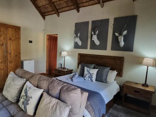 1 dormitorio con 1 cama y 1 sofá con cuernos en la pared en Paradise River Lodge, en Hoedspruit