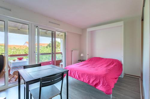 - une chambre avec un lit rose et une table dans l'établissement Charmant studio proche des plages d'Anglet, à Anglet