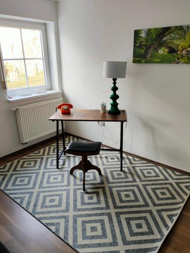 einen Schreibtisch mit einem Stuhl und einer Lampe auf einem Teppich in der Unterkunft Ferienwohnung Waldeule in Bad Kissingen