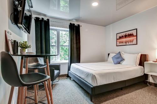 a bedroom with a bed and a desk and a chair at Location Au Sommet du Lac Magog in Magog-Orford