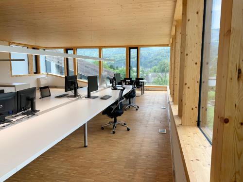 biuro z długimi biurkami z komputerami i oknami w obiekcie Ferienwohnung iq-Sports w mieście Bludenz