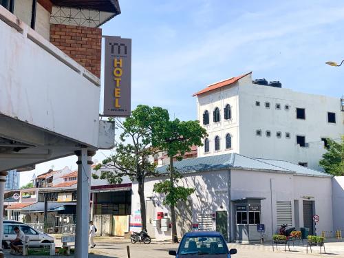 um carro estacionado em frente a um edifício branco em Mana Mana Hotel • Melaka • em Malaca
