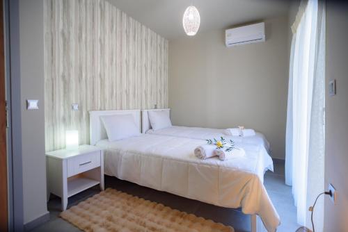 a small bedroom with a white bed with a night stand at Petousis Villas in Galatás