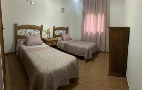 twee bedden in een kamer met roze kussens erop bij El Rincón de Caminito del Rey in Valle de Abdalagís