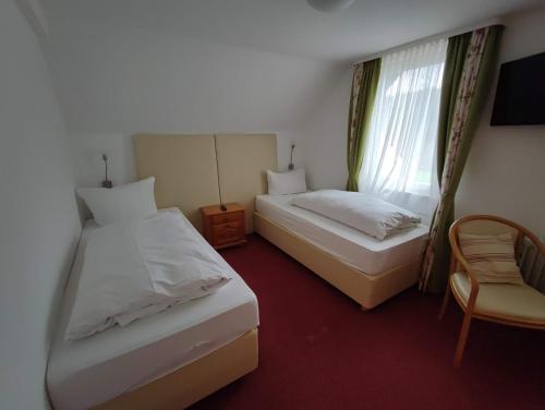 a bedroom with two beds and a chair and a window at Room in Guest room - Pension Forelle - double room no1 in Forbach