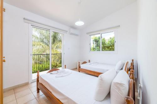 2 camas en una habitación con 2 ventanas en Thekla Oasis Villa, en Ayia Napa
