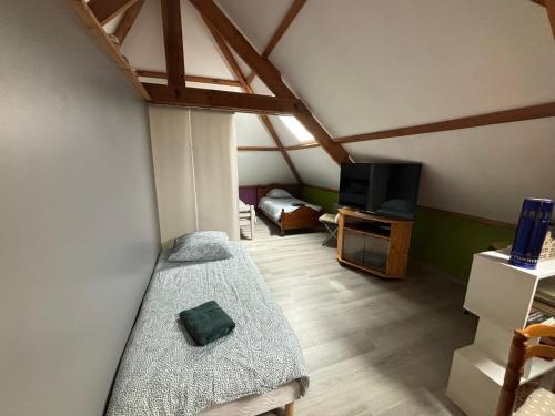 Cette chambre mansardée comprend un lit et une télévision. dans l'établissement À l'orée du bois, à Étaples