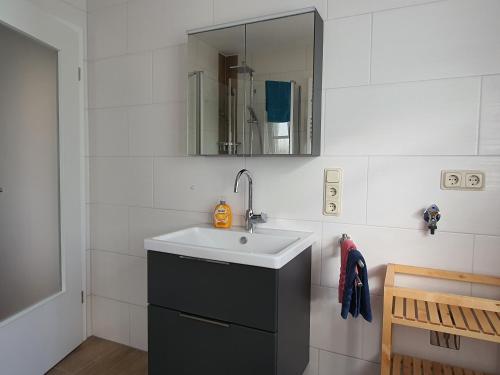 ein Bad mit einem Waschbecken und einem Spiegel in der Unterkunft Haus am Bürgerpark Hage EG in Hage
