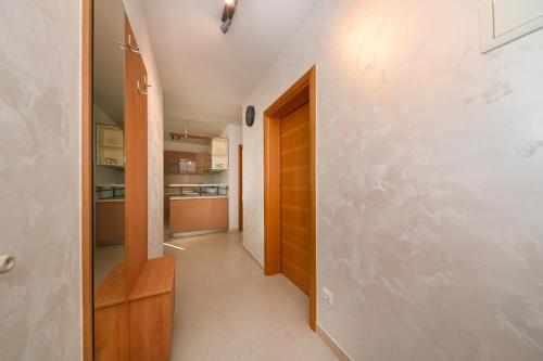 a hallway leading to a kitchen with a wooden door at APARTMANI PETRA in Vir