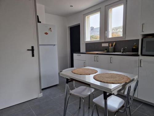 une cuisine avec une table, des chaises et un réfrigérateur dans l'établissement Le 4.02 appartement proche du centre, à Lannion