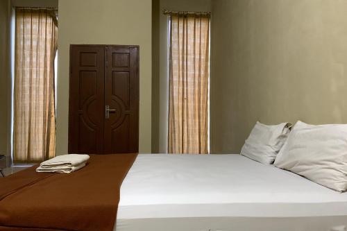 a bedroom with a large white bed with two pillows at OYO 93876 Athirah Kost in Tolo