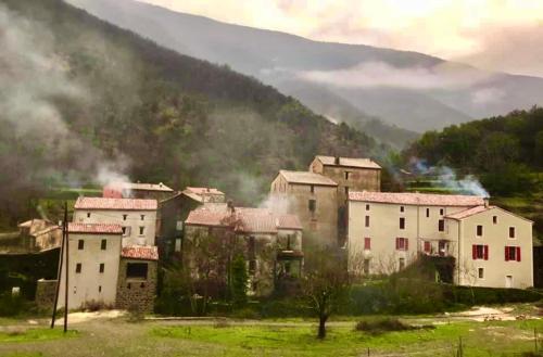 a village in the mountains with smoke in the background at Grande maison cévenole authentique in Valleraugue