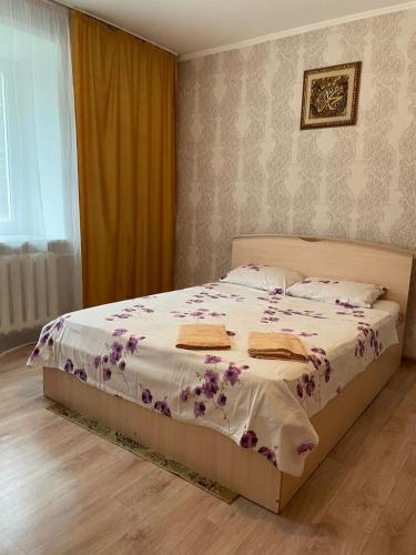 Un dormitorio con una cama con flores púrpuras. en Маринад, en Petropavlovsk