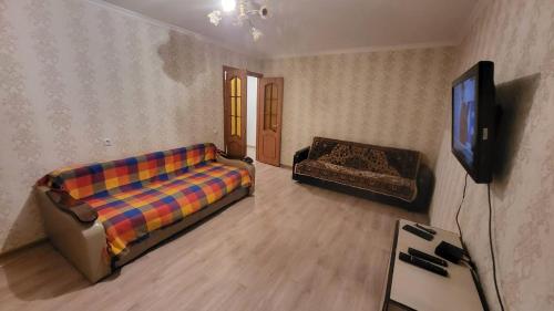 ein Wohnzimmer mit einem Sofa und einem TV in der Unterkunft Маринад in Petropawlowsk