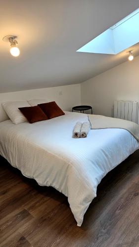 une chambre avec un grand lit blanc avec deux oreillers dans l'établissement Appartement Le New-York, à Cholet