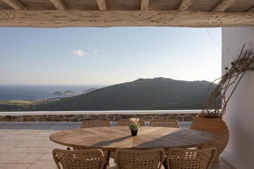 een houten tafel op een terras met uitzicht op de oceaan bij Mykonian Icon Villa in Mykonos-stad
