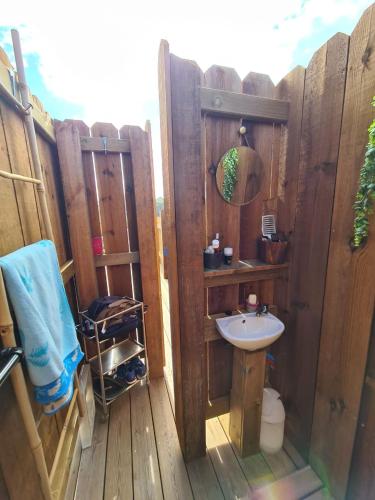 La salle de bains est pourvue d'un lavabo et d'une clôture en bois. dans l'établissement LE DODO LĖ LA, à Saint-Julien-en-Born