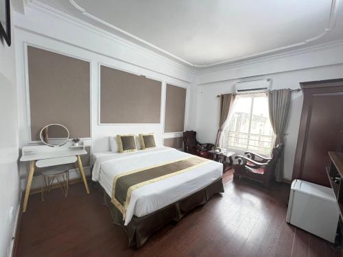 a bedroom with a bed and a desk and a window at Khách Sạn Hồng Nhung in Yen Bai