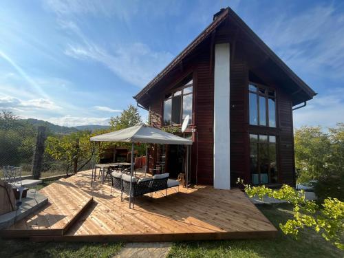 ein Haus mit einer Terrasse mit einem Tisch und einem Sonnenschirm in der Unterkunft Large Luxury Chalet in Raduil, nr Borovets - hot tub, views, Wi-Fi in Raduil