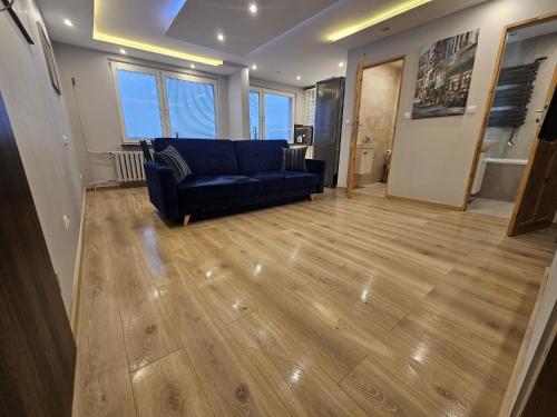a living room with a blue couch and wooden floors at City Sense - Apartament z widokiem na góry i miasto in Bielawa