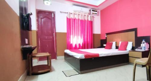 a bedroom with a bed with pink walls and a red door at Hotel Samrat Palace Puri Near Sea Beach Excellent Service in Puri