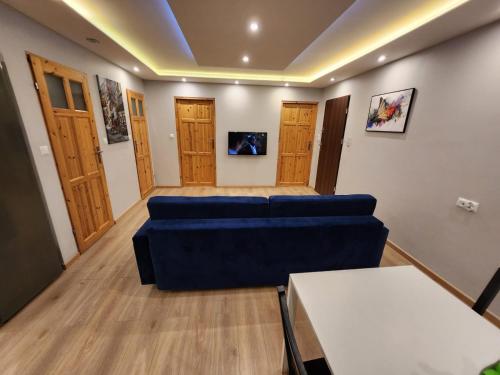 a living room with a blue couch and wooden floors at City Sense - Apartament z widokiem na góry i miasto in Bielawa
