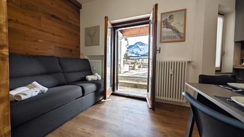 a living room with a couch and an open door at Hostdomus - Royal Oak in Sestriere