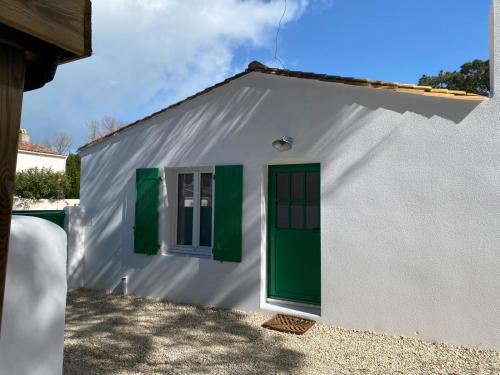 Casa blanca pequeña con puertas y ventanas verdes en Calme et tranquillité -Ile de Ré, en Rivedoux-Plage