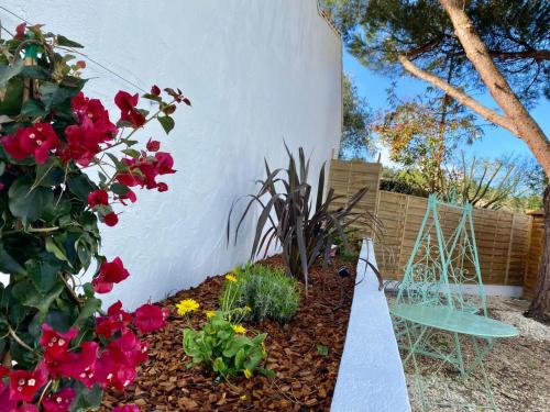 a garden with red flowers and a blue chair at Calme et Tranquillité in Rivedoux-Plage