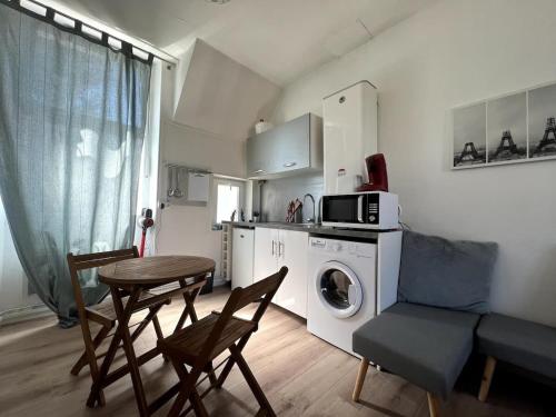 eine Küche mit einem Tisch, Stühlen und einer Mikrowelle in der Unterkunft V2 Studio Proche Disney Village Nature in Villiers-sur-Morin