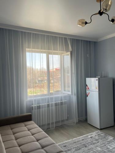 Elle comprend un salon avec un réfrigérateur et une fenêtre. dans l'établissement Карасу новый чистый апарт-отель, à (( Gornyy Gigant ))