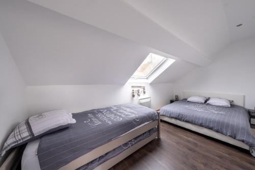 two beds in a white room with a window at D1 Maison de Charme proche Disney Val d'Europe in Dammartin-sur-Tigeaux