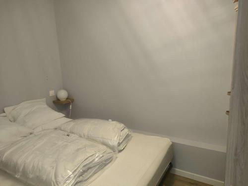 - un lit non aménagé dans une chambre dotée d'un mur blanc dans l'établissement Ref 151 - Appartement T1bis Terrasses de Kerjouanno vue mer, à Arzon