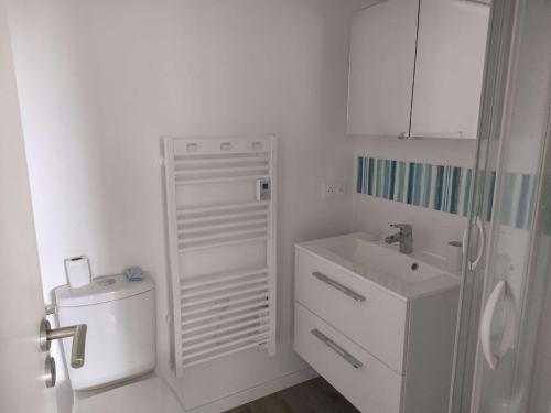 une salle de bain blanche avec des toilettes et un lavabo dans l'établissement Ref 151 - Appartement T1bis Terrasses de Kerjouanno vue mer, à Arzon
