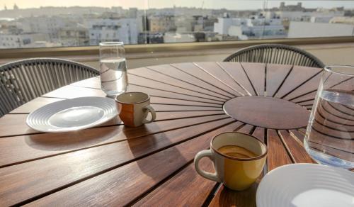 a wooden table with a cup of coffee and an umbrella at Penthouse With Sunny Terrace in Msida
