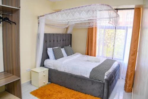 a bedroom with a canopy bed and a window at Dala Suites in Kakamega