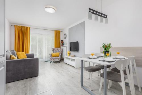 a white living room with a table and a couch at Elegant Apartment Na Wydmach with Balcony and Parking by Renters in Międzywodzie