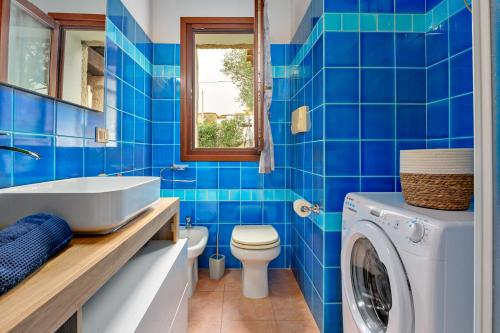 a blue tiled bathroom with a washing machine at Villa Quattro Cuori in San Teodoro
