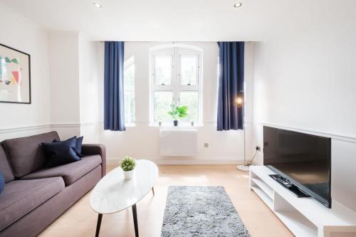 uma sala de estar com um sofá e uma televisão em London Fitzrovia CityApartmentStay em Londres