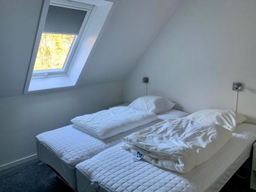 ein weißes Bett in einem Zimmer mit Fenster in der Unterkunft 2 voksne + 2 børn in Læsø