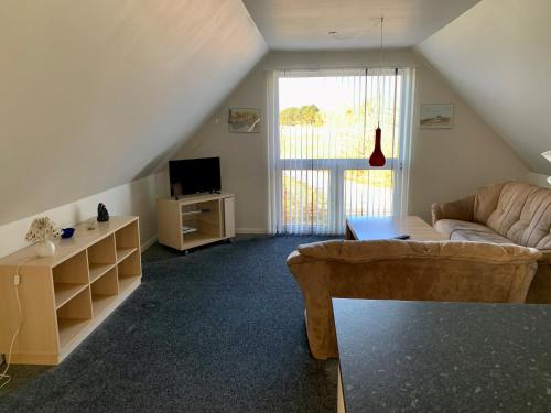 ein Wohnzimmer mit einem Sofa und einem TV in der Unterkunft 2 voksne + 2 børn in Læsø