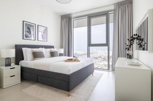 a white bedroom with a large bed and a window at Frank Porter - 1 Residences in Dubai