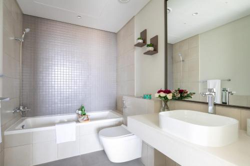a bathroom with a sink and a tub and a toilet at Frank Porter - 1 Residences in Dubai