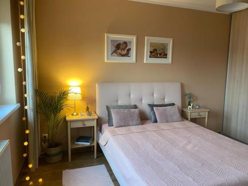 a bedroom with a bed with two tables and two pictures on the wall at Colibri Apartament Lubniewice in Lubniewice