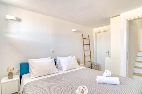 a white bedroom with a bed with towels on it at Villamar - Private villa with pool in Naoussa in Kampos Paros