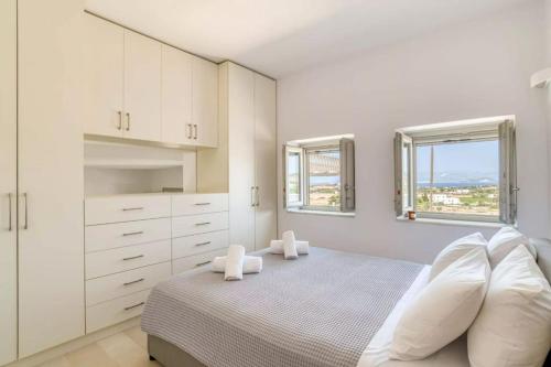 a white bedroom with a bed and two windows at Villamar - Private villa with pool in Naoussa in Kampos Paros