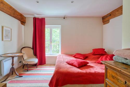 a bedroom with a red bed and a table and a window at Centre Ahimsa in Verrières-le-Buisson